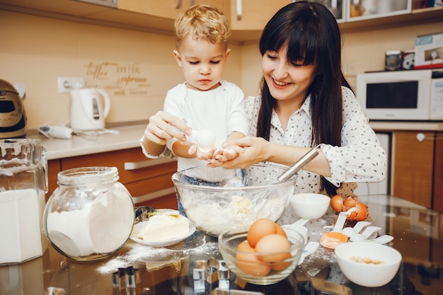 jonge moeder in een wit overhemd bereiden van voedsel thuis in de keuken met haar zoontje