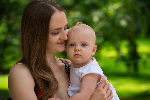 Jonge moeder knuffelen baby dochter op de achtergrond van de natuur Gelukkig moederschap pfrenthood