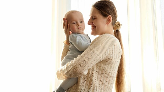 Foto jonge moeder knuffelen en glimlachen naar haar zoontje in zonsonderganglicht concept gezinsgeluk en ouderschap