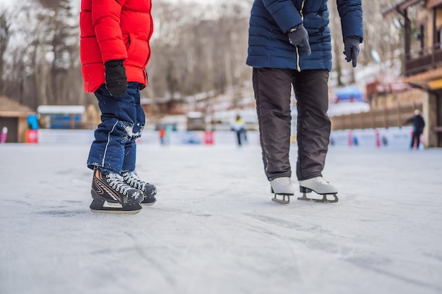 Foto jonge moeder leert haar kleine zoon schaatsen op een schaatsbaan. het gezin geniet van de winter op de schaatsbaan buiten.