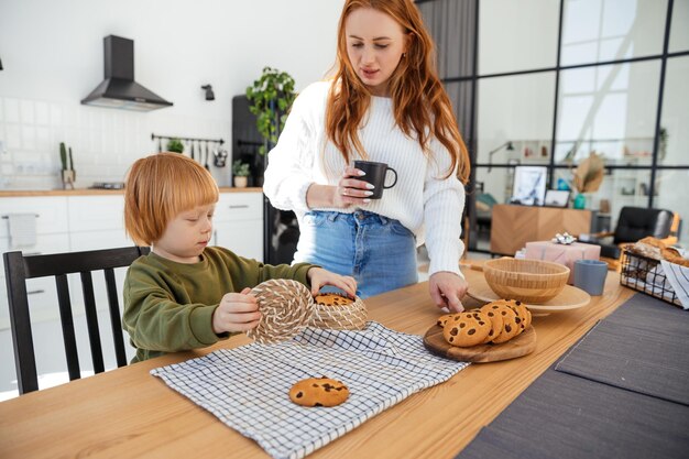 jonge moeder leert haar roodharige zoon koekjes bakken