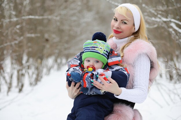 Jonge moeder loopt op een winterdag met een baby in haar armen in het park