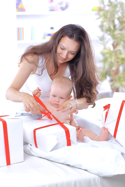 Jonge moeder maakt het lint op de geschenkdozen los. Vakantieconcept