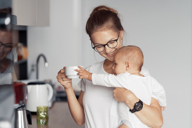 Jonge moeder met baby hebben plezier in de keuken thuis