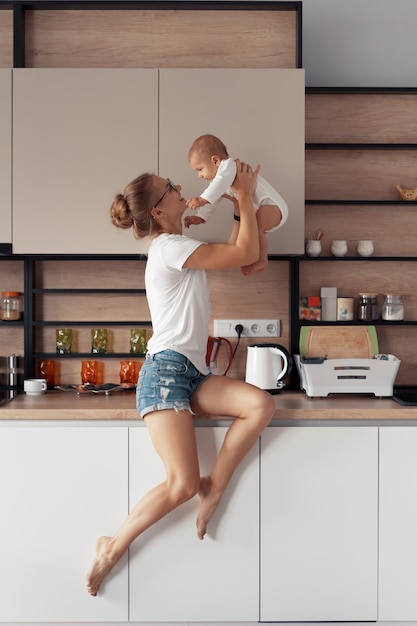 Jonge moeder met baby hebben plezier in de keuken thuis