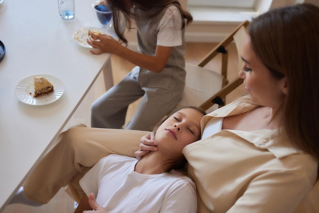 Foto jonge moeder met een mooie dochter drinkt thee in de keuken