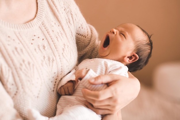 Jonge moeder met gierende baby op handen in de kamer Goedemorgen Moederschap