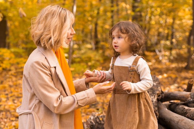 Jonge moeder met haar dochtertje in een herfst park herfst seizoen ouderschap en kinderen concept