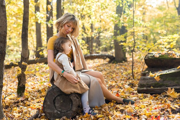 Jonge moeder met haar dochtertje in een herfstpark. Herfstseizoen, ouderschap en kinderen concept.