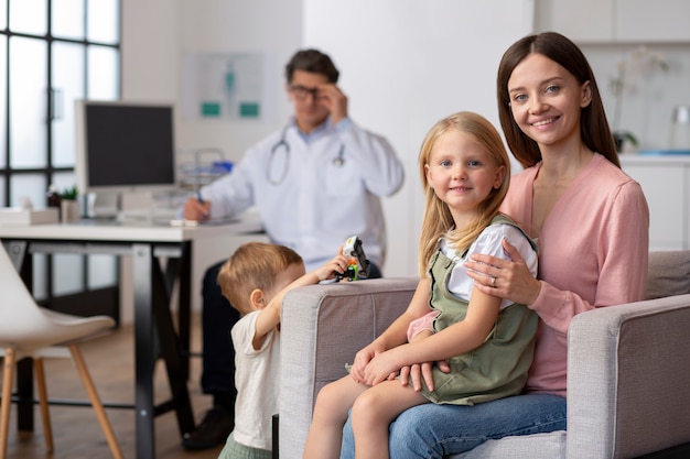 Foto jonge moeder met haar kinderen op afspraak bij kinderarts