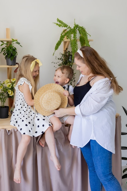 jonge moeder met haar zoon en dochter lacht knuffels en speelt binnenshuis Concept van gelukkig leuk gezin