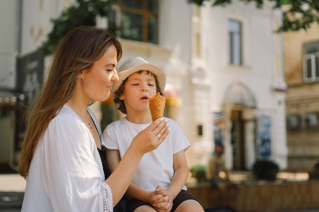 jonge moeder met kleine jongen buiten in de zomer die ijs eet, zomervoedsel en zomertijd