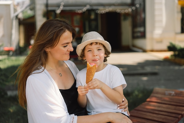 Jonge moeder met kleine jongen buiten in de zomer die ijs eet, zomervoedsel en zomertijd