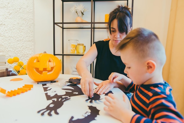 Jonge moeder met peuterzoon die ambachtelijke spinnen maakt voor Halloween-vakantie