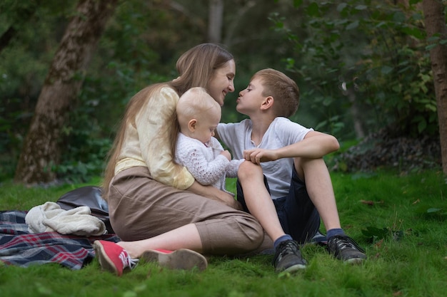 Jonge moeder met twee kinderen rustend op de natuur Moeder liefde en zorg Gelukkig gezin