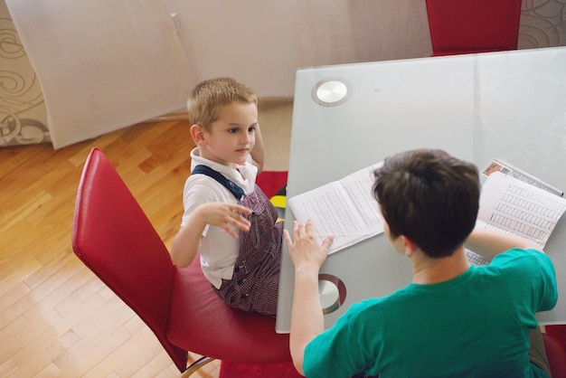 jonge moedervrouw die thuiswerk doet met een basisschooljongen thuis in de keuken