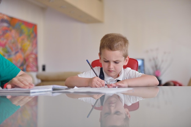 jonge moedervrouw die thuiswerk doet met een basisschooljongen thuis in de keuken