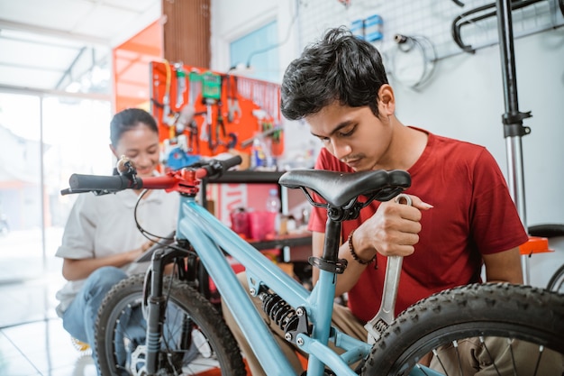 Jonge monteur die een nieuwe fiets monteert met een moersleutel in de winkel