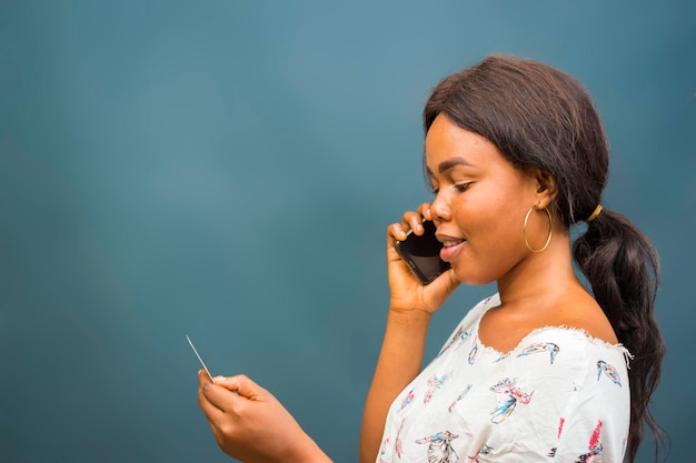jonge mooie Afrikaanse dame die opgewonden is over het telefoontje dat ze ontvangt van haar mobiel, mobiele telefoon, telefoon en haar creditcard vasthoudt