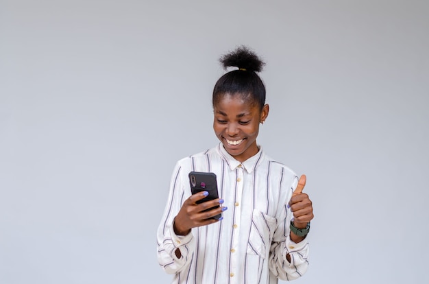 Jonge mooie Afrikaanse dame die zich overenthousiast voelt over wat ze op haar verkooptelefoon zag