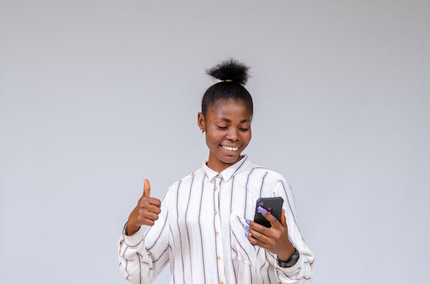 Jonge mooie Afrikaanse dame die zich overenthousiast voelt over wat ze op haar verkooptelefoon zag
