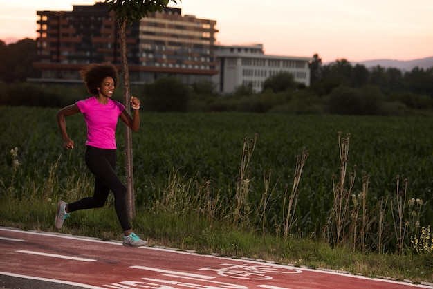 jonge mooie Afro-Amerikaanse vrouw geniet van hardlopen buiten mooie zomeravond in de stad