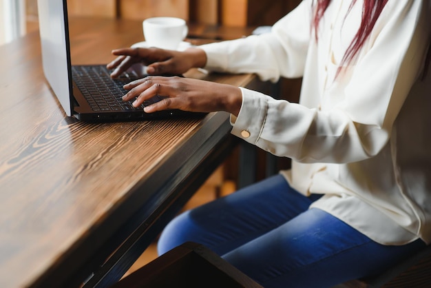 Jonge mooie afro-amerikaanse zakenvrouw die laptop gebruikt terwijl ze in café werkt