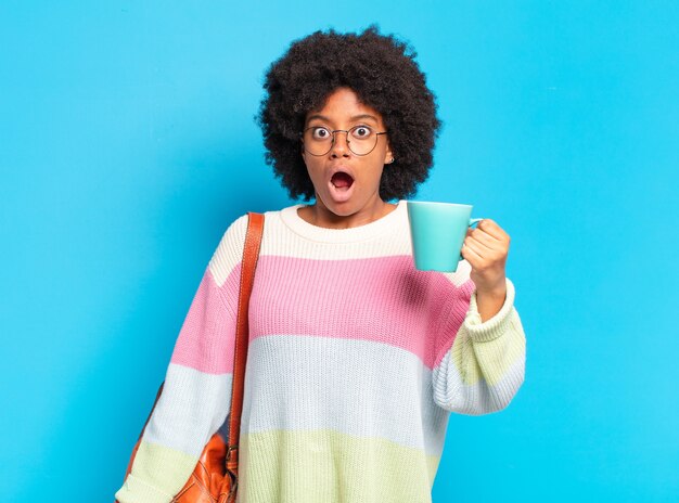 Jonge mooie afro student vrouw met een koffiekopje