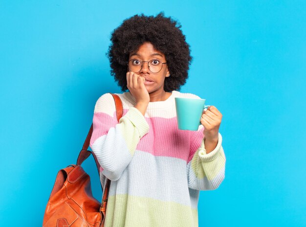 Jonge mooie afro student vrouw met een koffiekopje