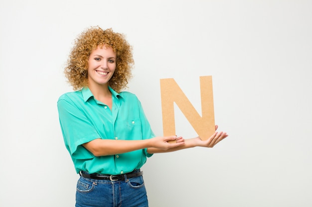 Jonge mooie afro vrouw opgewonden, blij, vrolijk, met de letter N