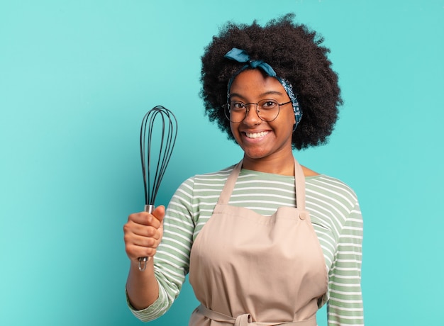 Jonge mooie afrovrouwenchef-kok met een mixer