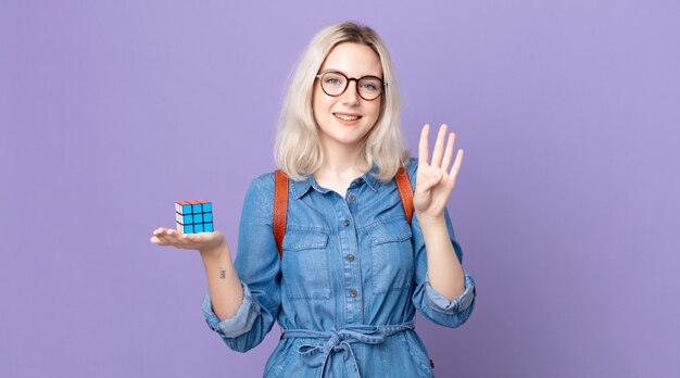 Jonge mooie albino-vrouw die lacht en er vriendelijk uitziet, nummer vier laat zien en een intelligentiespel oplost