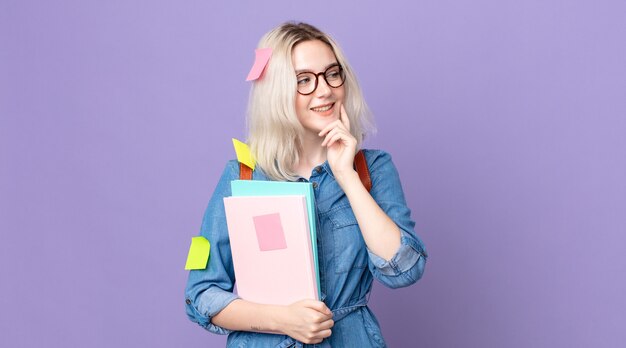 Jonge mooie albino-vrouw die lacht met een gelukkige, zelfverzekerde uitdrukking met de hand op de kin. studentenconcept