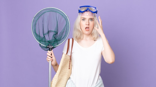 Jonge mooie albino vrouw schreeuwen met handen omhoog in de lucht met bril en een visnet