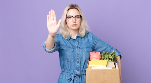 Jonge mooie albinovrouw die ernstig kijkt die open palm toont die stopgebaar maakt. ontslag concept