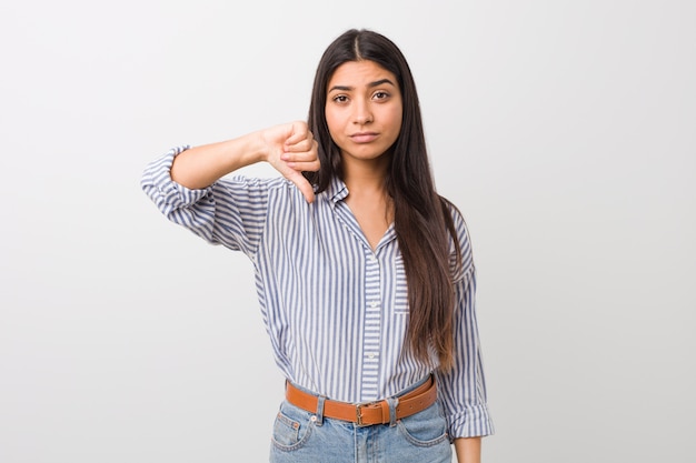 Jonge mooie Arabische vrouw die een afkeergebaar, duimen neer tonen. Meningsverschil .