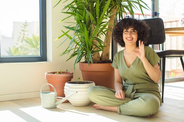 Jonge mooie Arabische vrouw thuis, met een gieter en planten