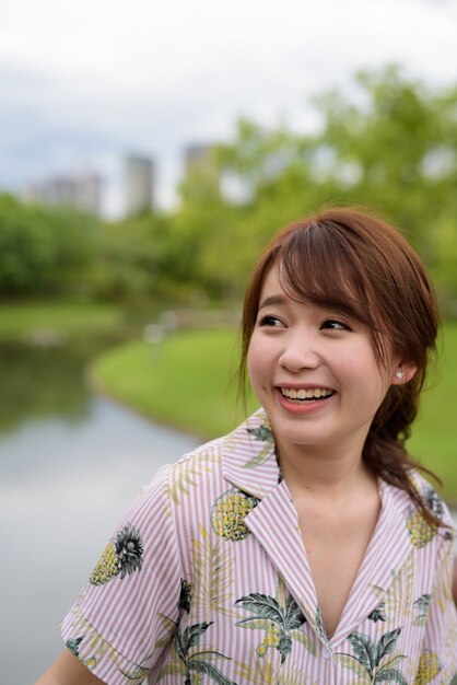 Jonge mooie Aziatische toeristische vrouw ontspannen in het park