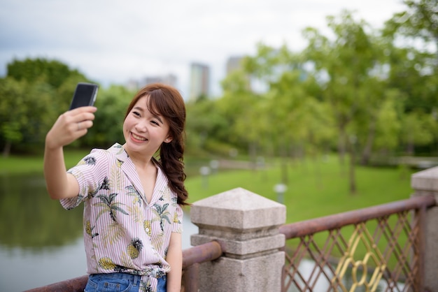 Jonge mooie Aziatische toeristische vrouw ontspannen in het park