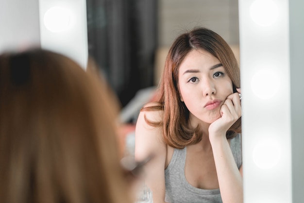 Jonge mooie aziatische vrouw die make-up in de buurt van spiegel