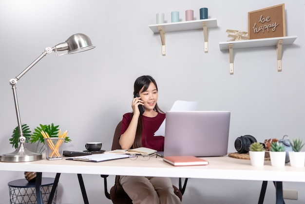 Jonge mooie Aziatische vrouw die thuis werkt