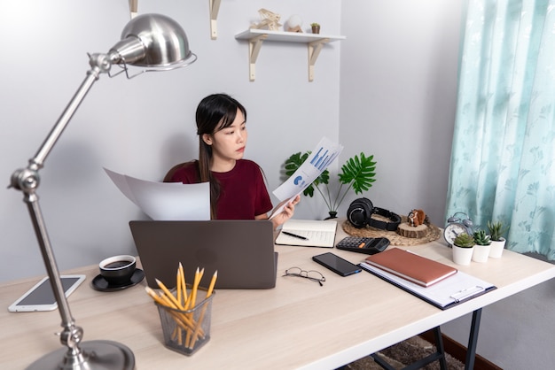 Jonge mooie Aziatische vrouw die thuis werkt