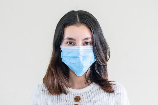 Jonge mooie aziatische vrouw die toont hoe een medisch masker te dragen