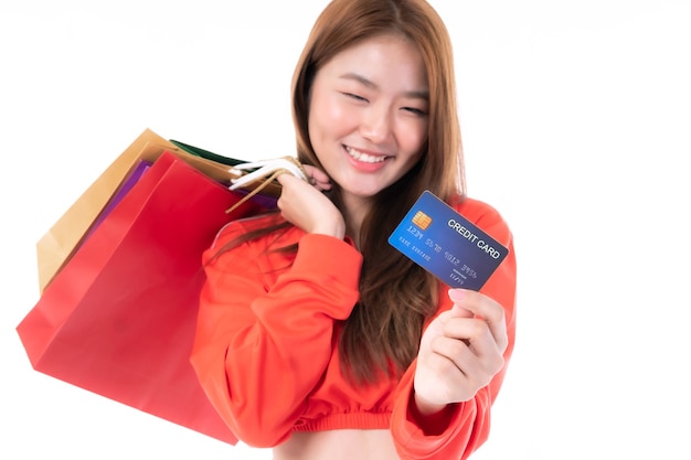 Jonge, mooie aziatische vrouw die veel boodschappentas vasthoudt en creditcard toont voor betaling winkelen geïsoleerd op een witte achtergrond - selectieve focus