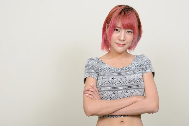 jonge mooie Aziatische vrouw met roze haren tegen witte muur