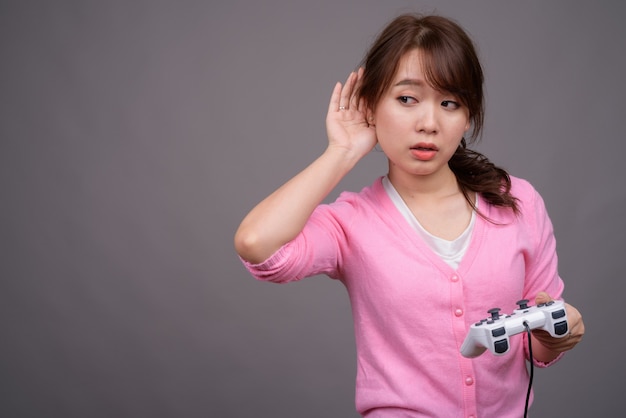 Jonge mooie Aziatische vrouw spelen met spelbesturing