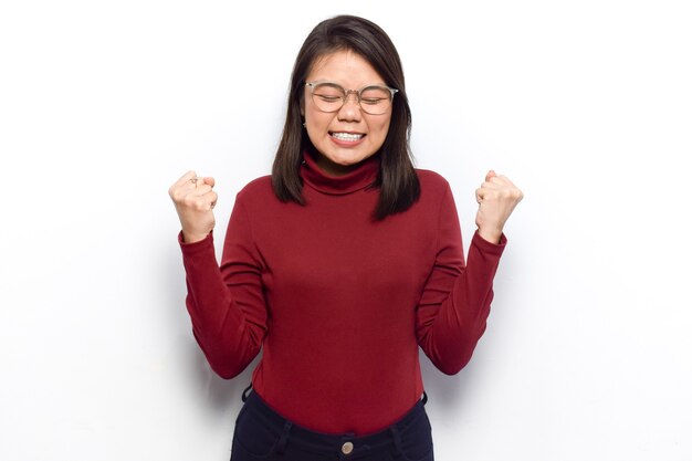 Jonge mooie Aziatische vrouwen kleden rood shirt geïsoleerd op een witte achtergrond doen wat pose