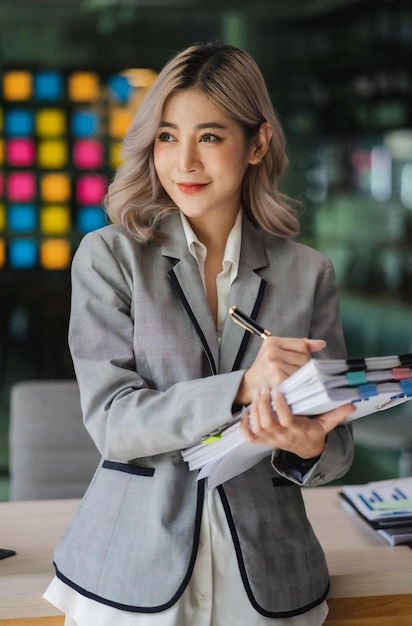 Jonge, mooie Aziatische zakenvrouw houdt papieren rekeningdocumenten informeel spreadsheet financieel Accountant-consulting werkstand review reportxA