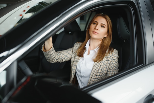 Jonge mooie bedrijfsvrouwenzitting in haar auto