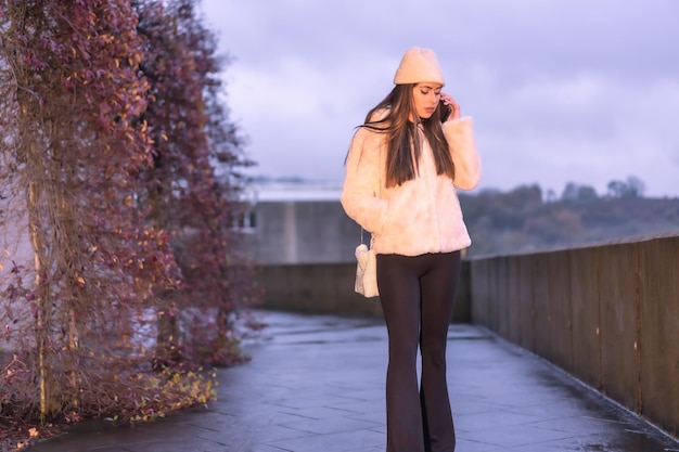 Jonge mooie blanke brunette die in de winter door de stad loopt en een roze wollen trui draagt
